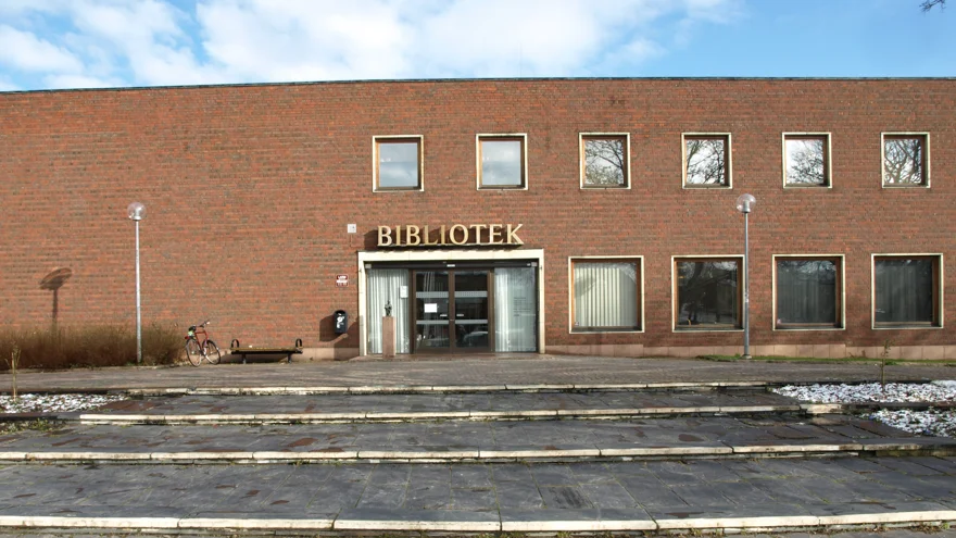 Tegelbyggnad i rött och med texten bibliotek över entrén