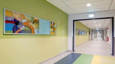 Målningar placerade på en gulgrön vägg i en korridor