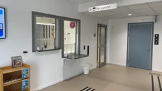 Ett fönster i den vita väggen ut receptionens lucka. I taket hänger en skylt där det står "reception".
