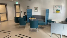 Väntrum med blåa och gråa fåtöljer, samt små vita bord.