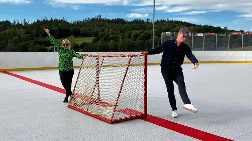 Två dansare håller på varsin sida av ett bandymål.
