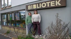 Mia-Marika Andin, bibliotekarie Horreds bibliotek och Louise Öjborg, bibliotekarie Fritsla bibliotek står utanför biblioteket i Horred. De står under en skylt där det står BIBLIOTEK.