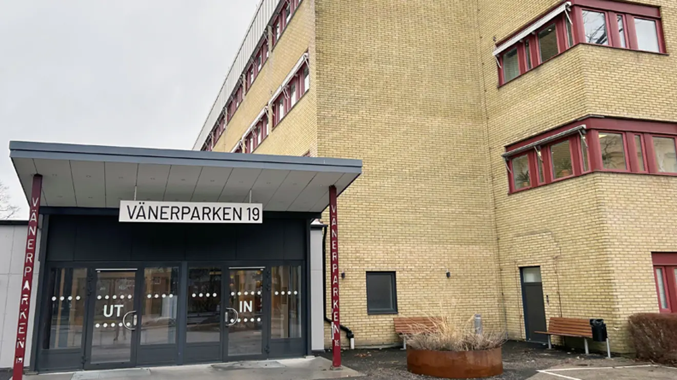 Glasad entré med tak till vänster om gul tegelbyggnad