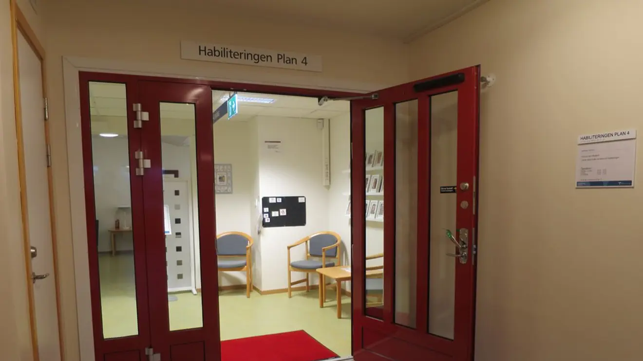 Entrédörr i glas med röda detaljer i korridor