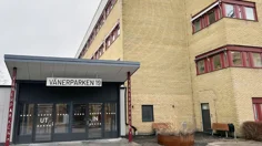 Entré med glaspartier brevid gul tegelbyggnad